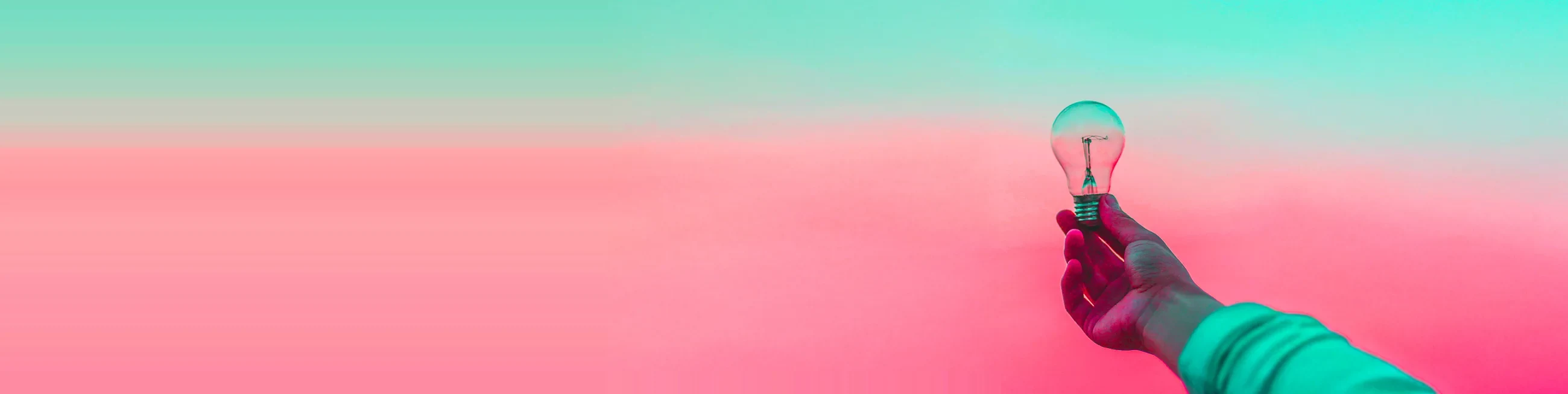 A hand holding a lightbulb against a pink and green gradient